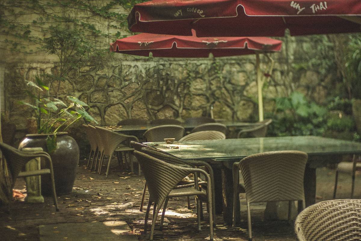 Side-by-side comparison showing traditional umbrella with center pole blocking table vs. cantilever umbrella providing open shade