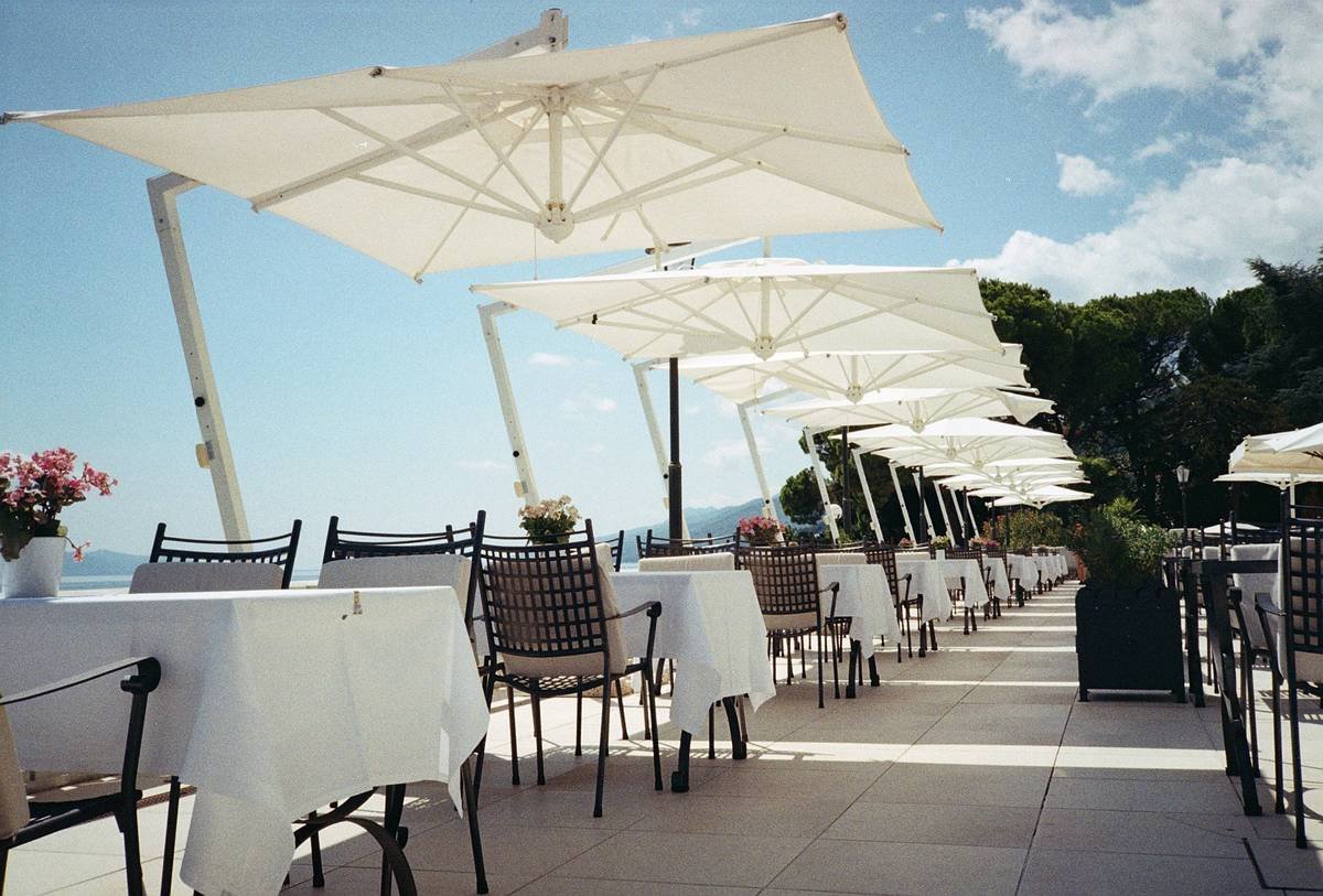 Side-by-side comparison: traditional center-pole umbrella vs. cantilever umbrella showing clear space under canopy