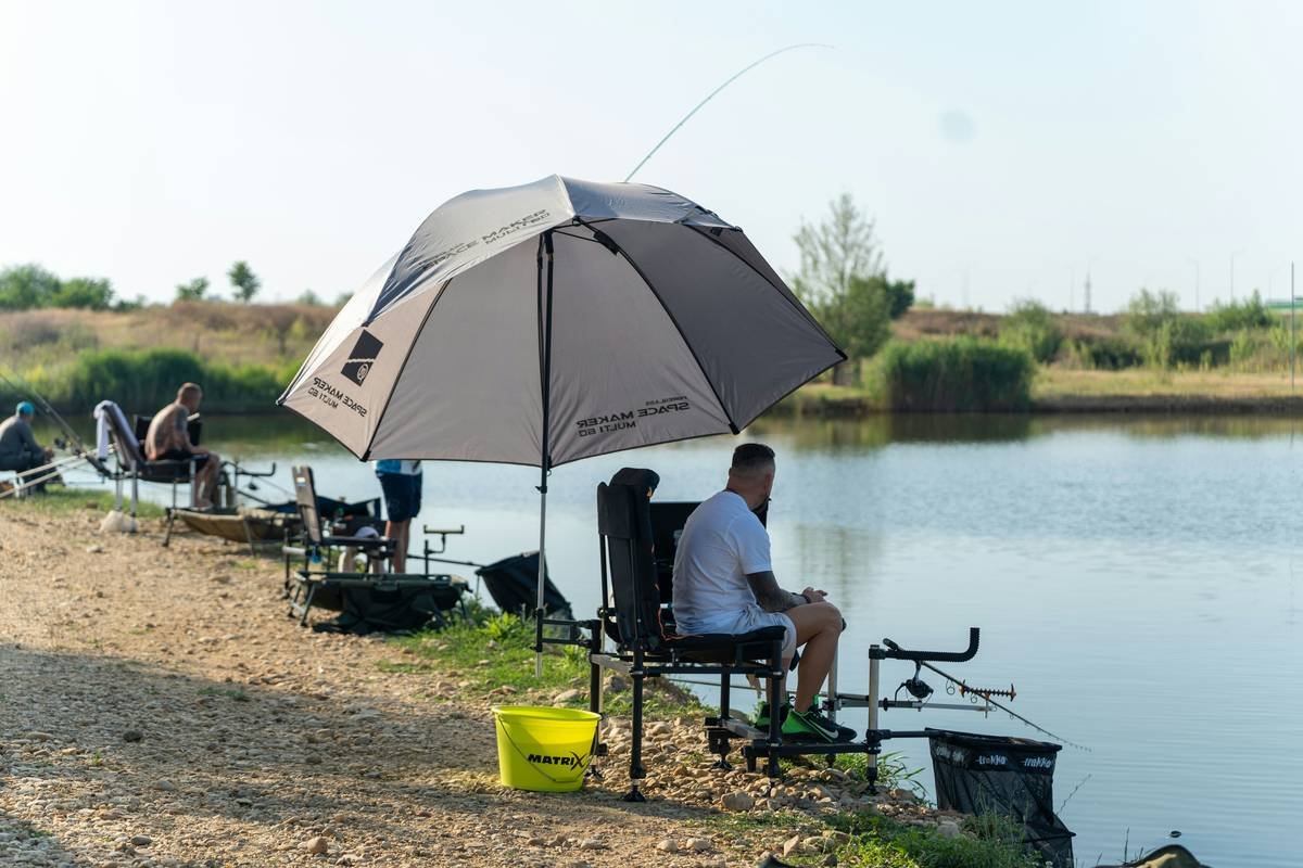 fishing umbrellas go outdoors beside a patio table with chairs, showing offset canopy and heavy base