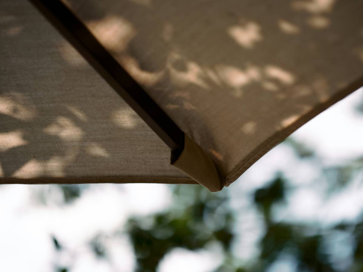 Black cantilever outdoor umbrella with uv protection casting shade over patio seating